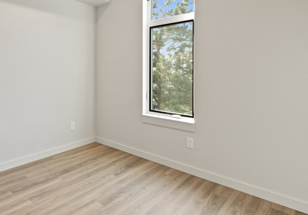 an empty room with wood floors and a window