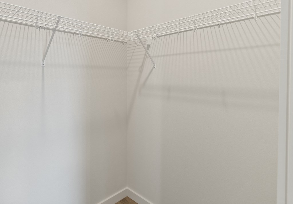 an empty walk in closet with white walls and white rods on the ceiling