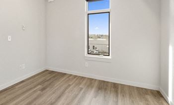 an empty room with a window and wooden floors