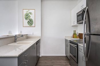 an empty kitchen with stainless steel appliances and white countertops