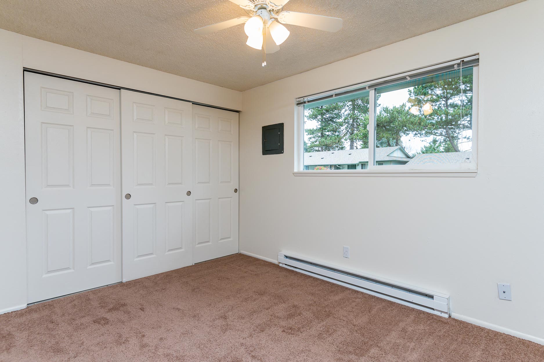 Pinewood Terrace Apartments | Second bedroom with closet doors, window and ceiling fan light.