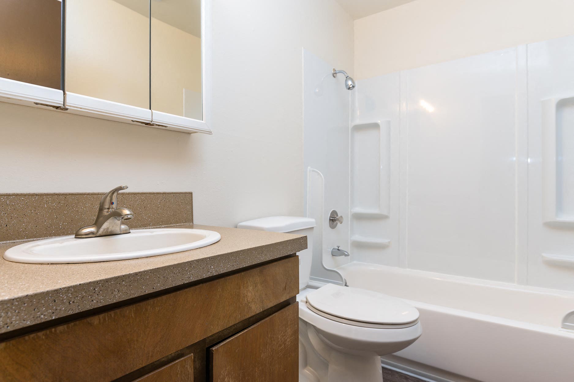 Pinewood Terrace Apartments | Bathroom with tub shower combo. Single vanity sink, mirror and cabinetry below.