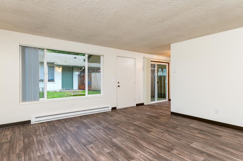 Pinewood Terrace Apartments | Living Room with large window, front door and view of patio sliding door in dining room. - Photo Gallery 1