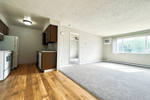 A kitchen with white appliances and wooden floors.