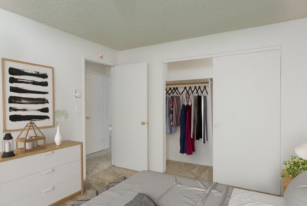 a bedroom with a closet and a bed and a dresser with clothes hanging on