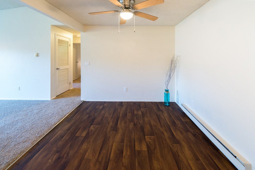 an empty living room with wood flooring and a ceiling fan