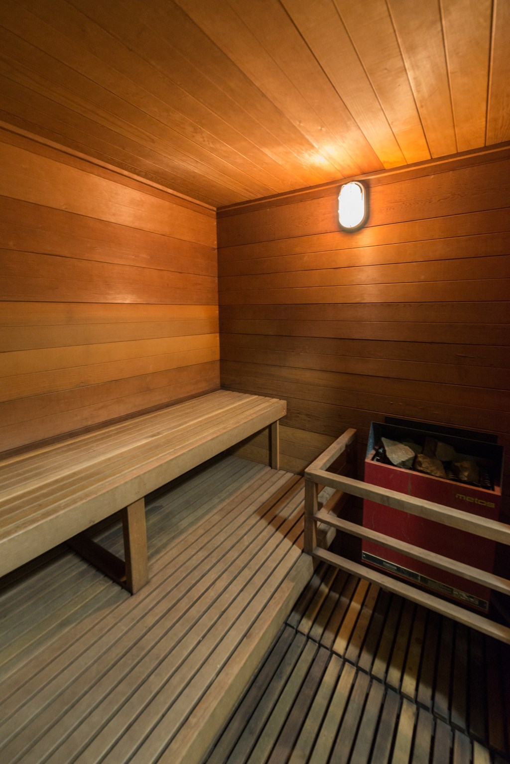a wooden sauna with a bench and a container of shoes