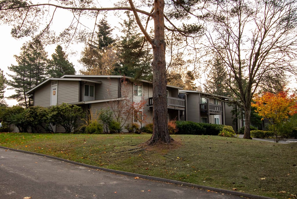 the exterior of an apartment building with a tree in the front