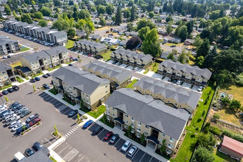 A bird's eye view of a residential area with multiple houses and a parking lot.