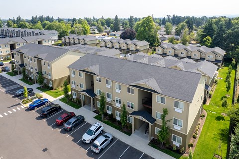Apartment complex with a parking lot in front.