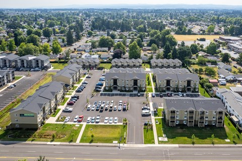A large apartment complex with a parking lot in front.