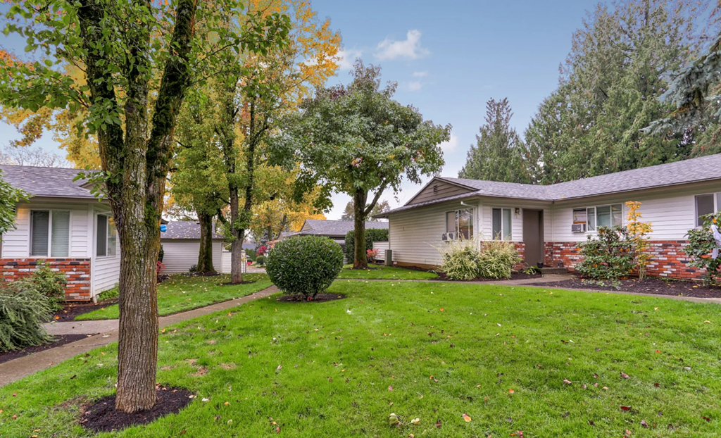 a yard in front of a white house with trees