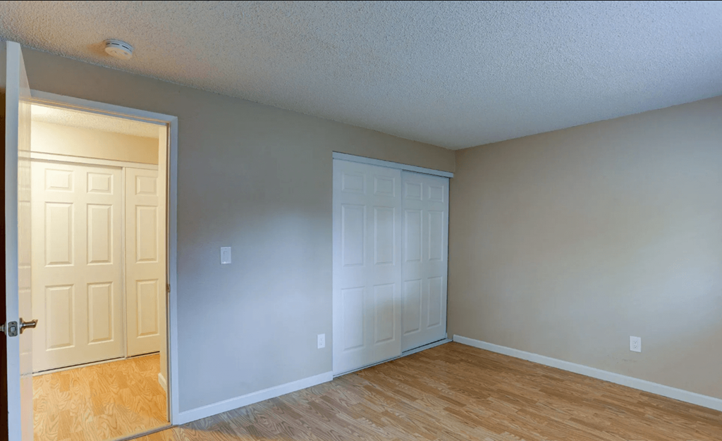 an empty living room with two doors and a wood floor