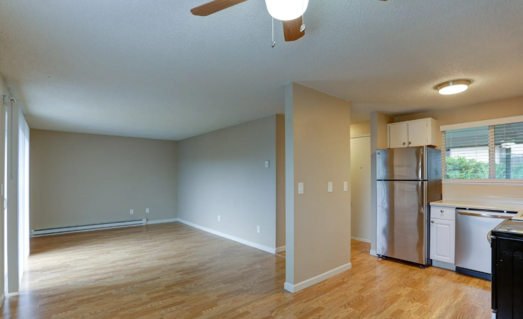 an empty kitchen and living room with a stainless steel refrigerator