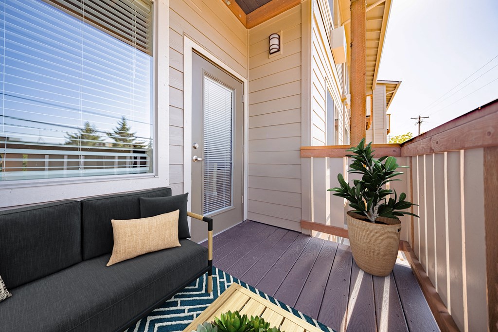 A balcony with a couch and a potted plant.