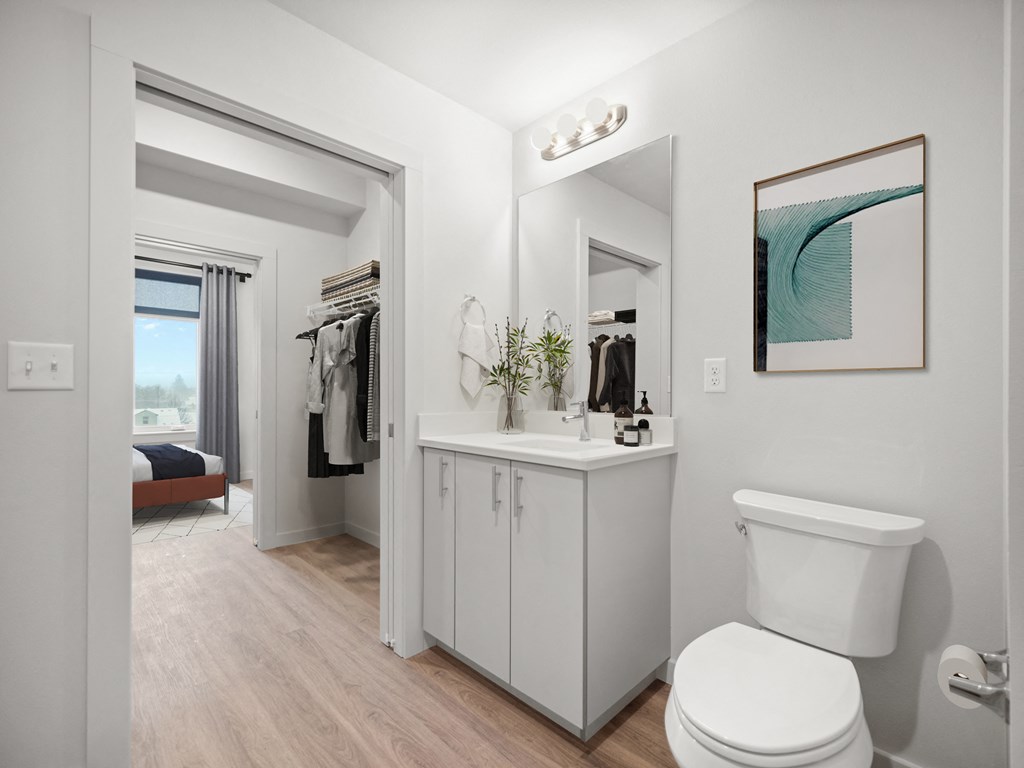 a white bathroom with a white toilet and a large mirror