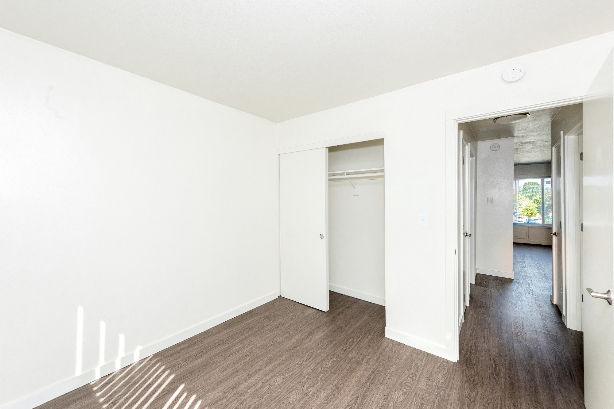 a living room with white walls and wood floors and a closet