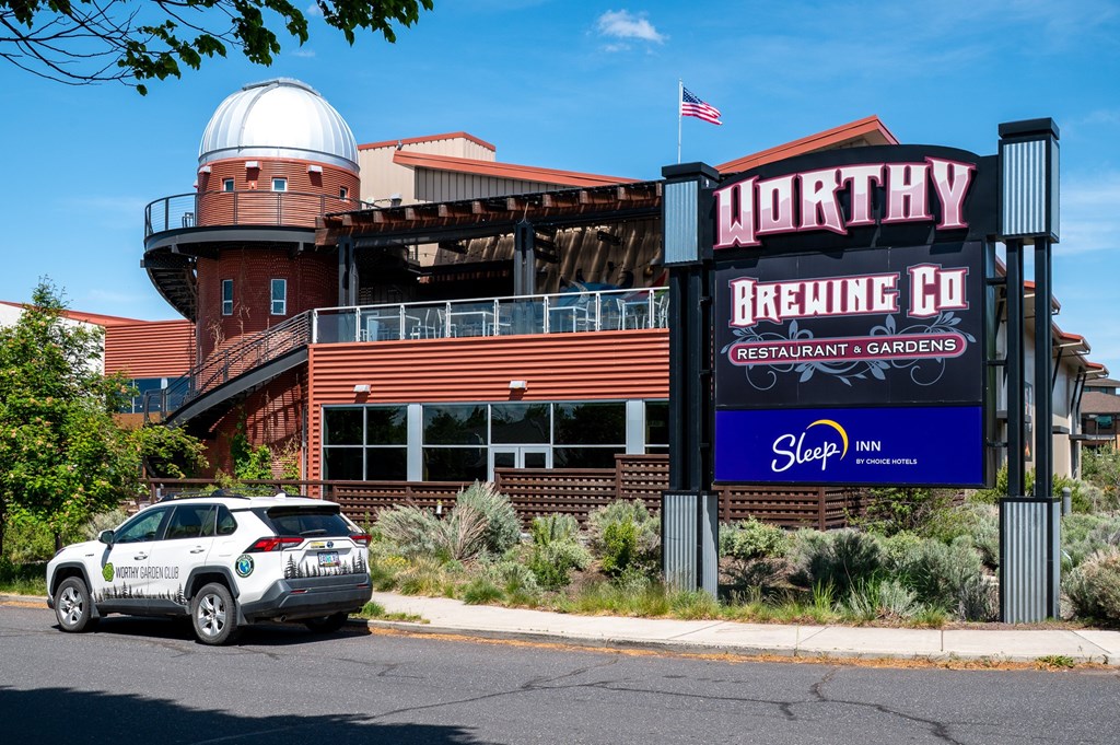 A car is parked in front of a building with a sign that says WORTHY BREWING CO.