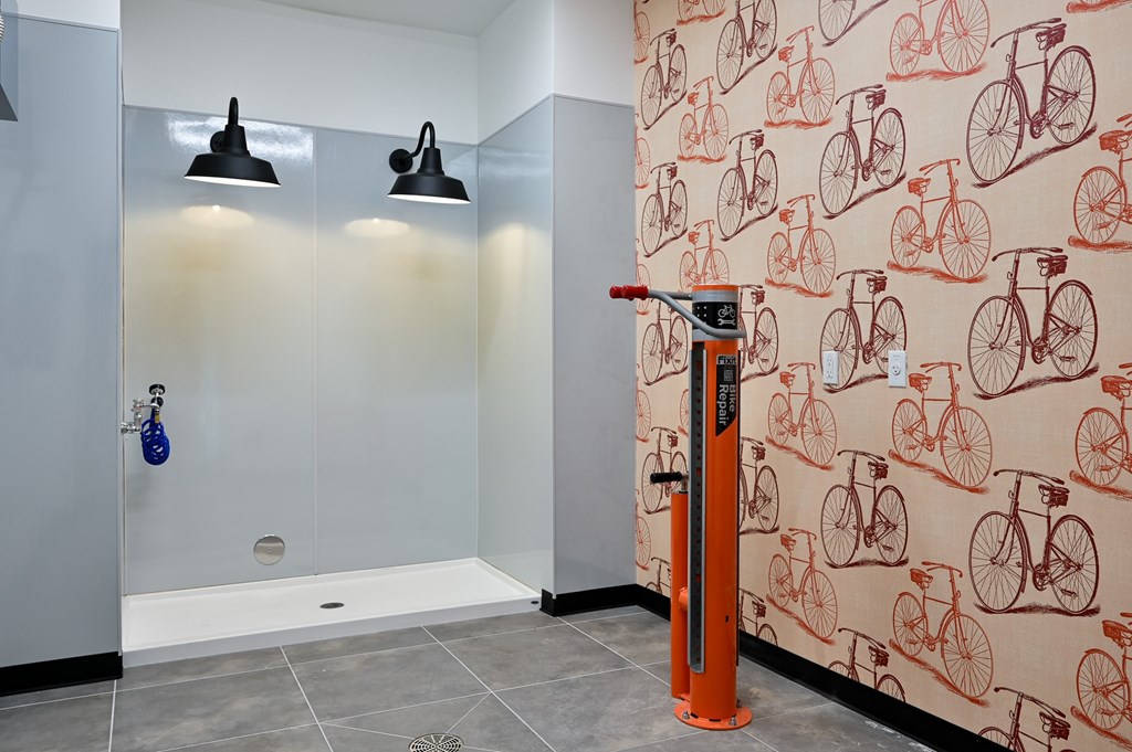 A bathroom with a bicycle patterned wallpaper and a shower with a glass door.