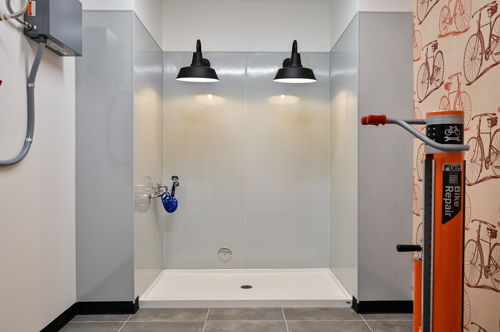 A bathroom with a shower and a bicycle patterned wallpaper.