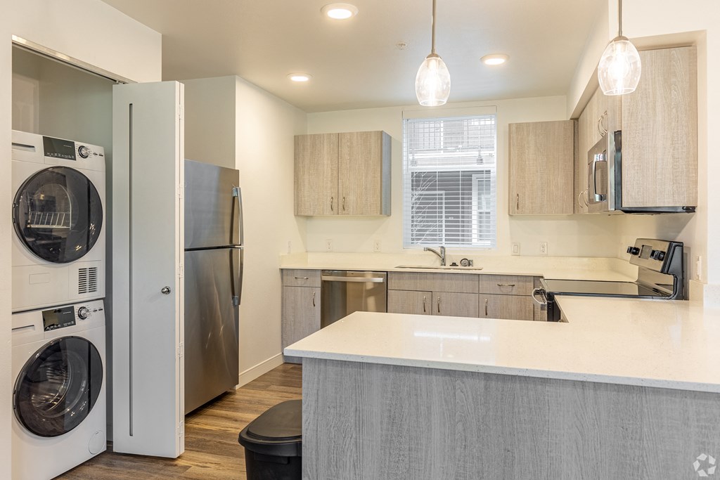 Vancouver, WA Student Apartments - 134th Street Lofts - Kitchen with Wood Plank Vinyl Flooring, Quartz Countertops, Stainless Steel Appliances, Wood-Style Cabinets, and an In-Unit Washer and Dryer