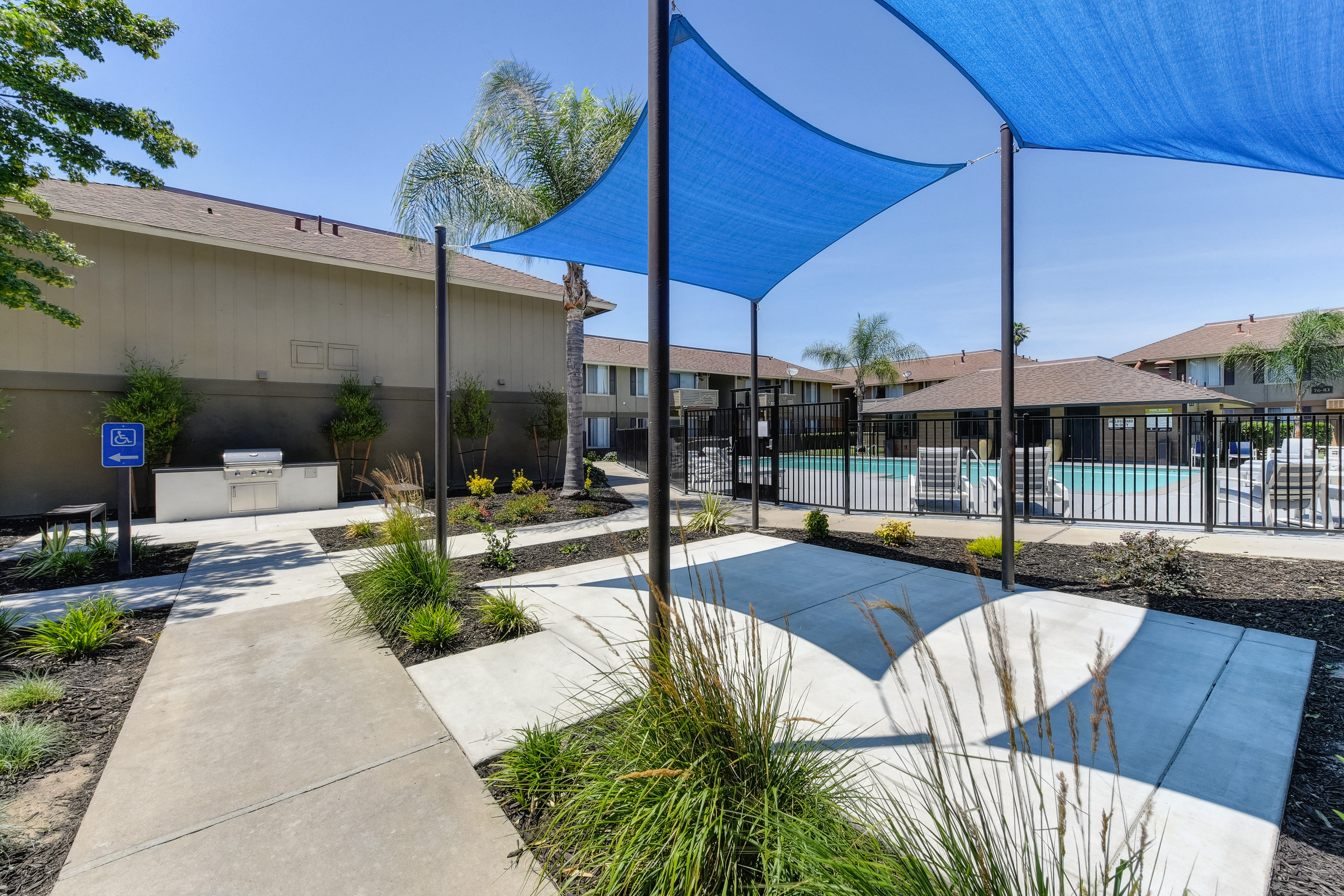 Exterior Courtyard with sunshade over concrete pad. Pathway leading to outdoor BBQ area.