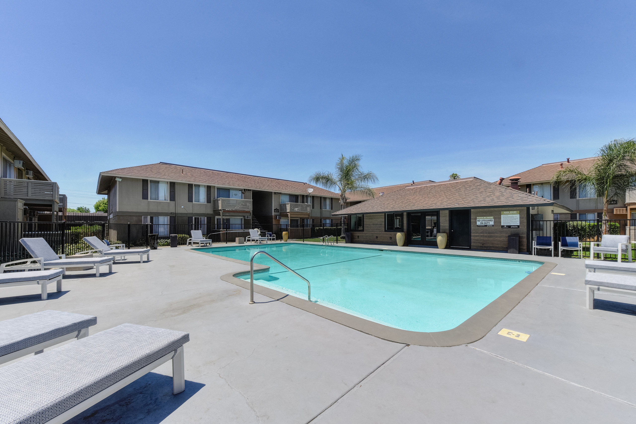 Chardonnay Ridge outdoor swimming pool surrounded by concrete sundeck. Lounge chairs spread out.