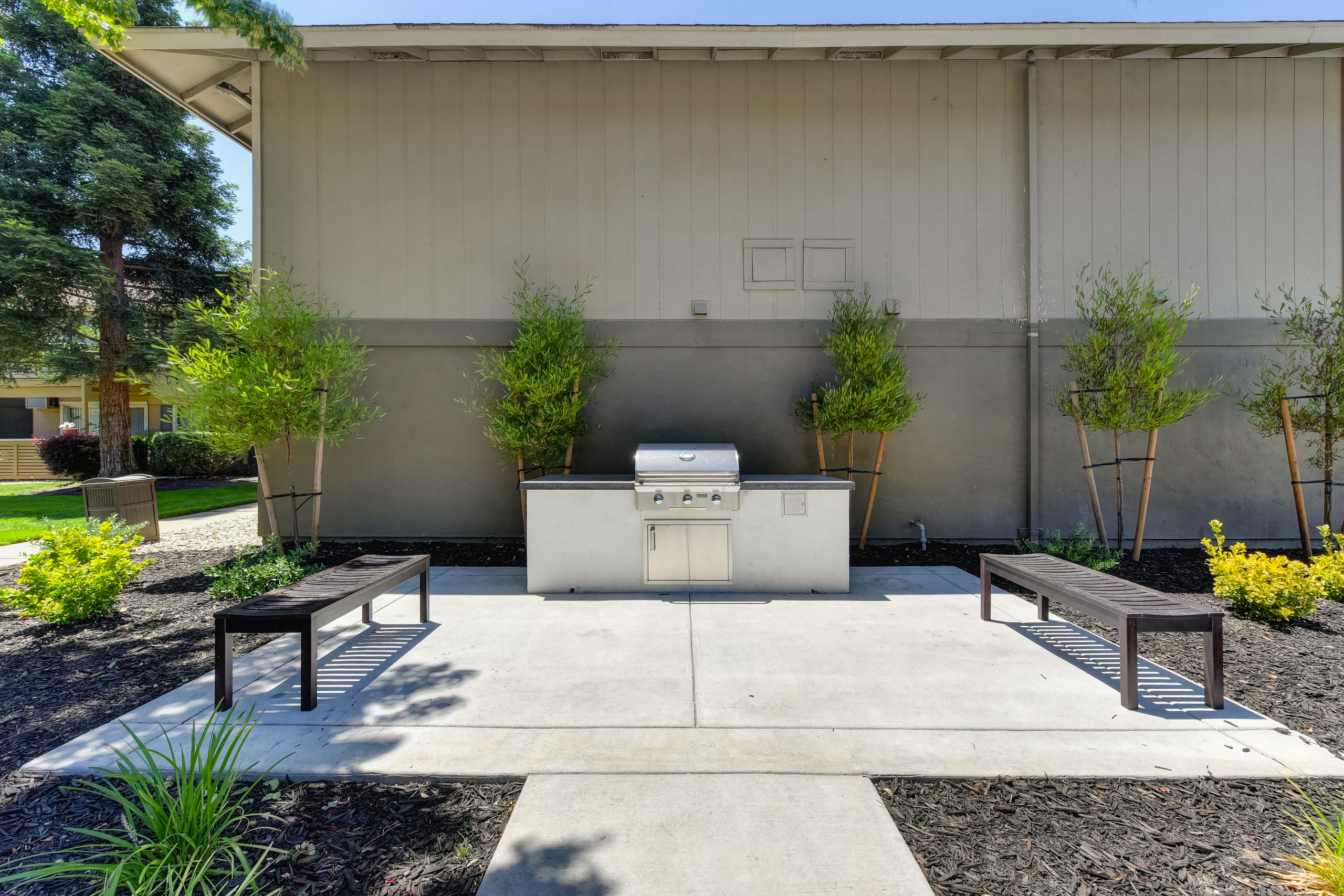 Exterior BBQ grill and courtyard with bench seating. area