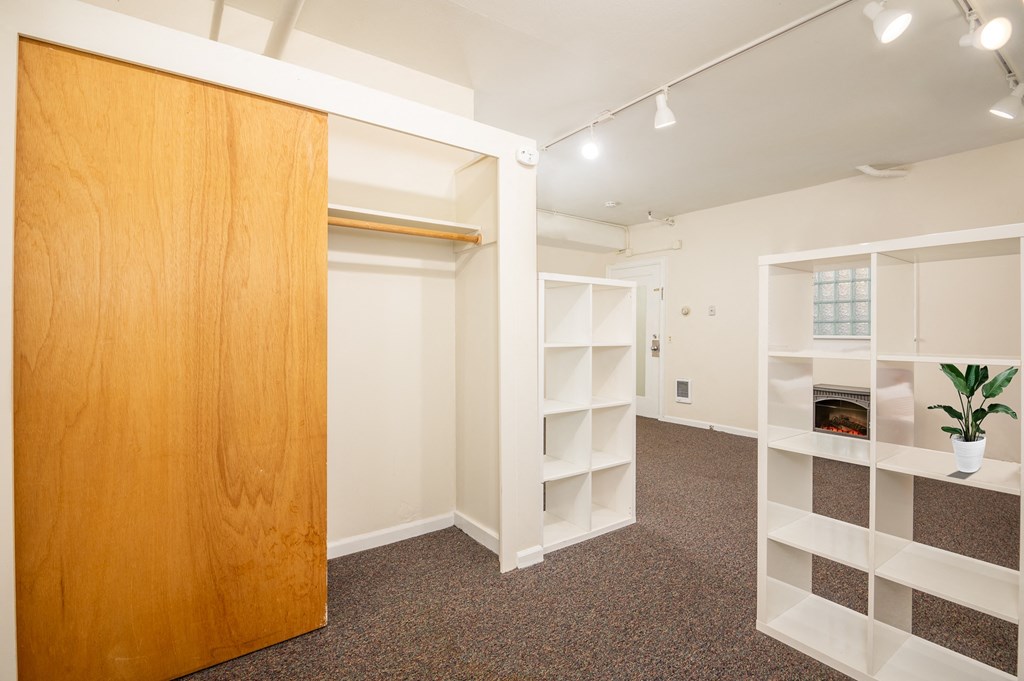a walk in closet with a wooden door and white shelves