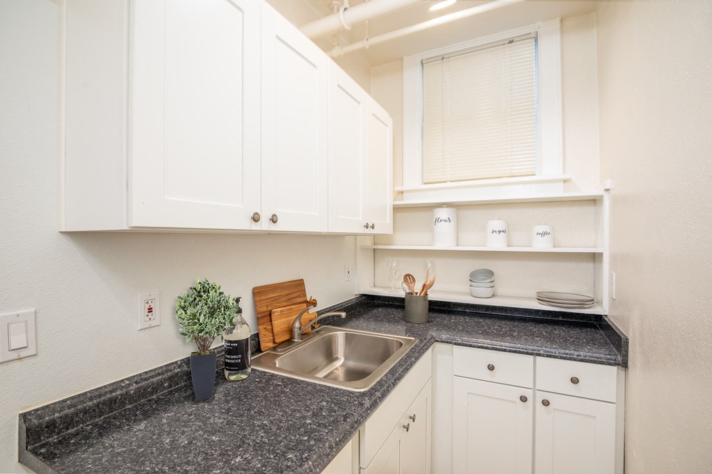a kitchen with white cabinets and granite counter tops and a sink