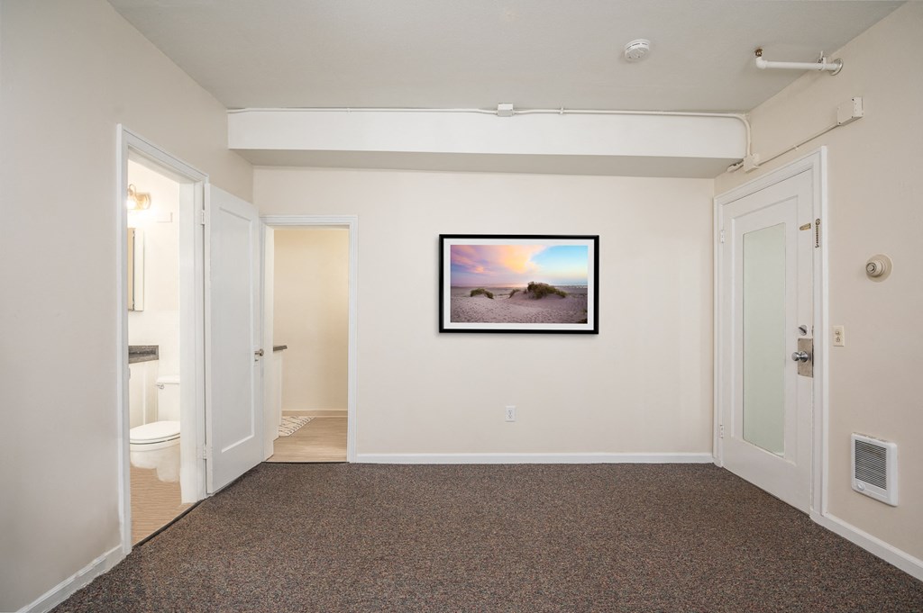 a living room with a painting on the wall and a door to a bathroom