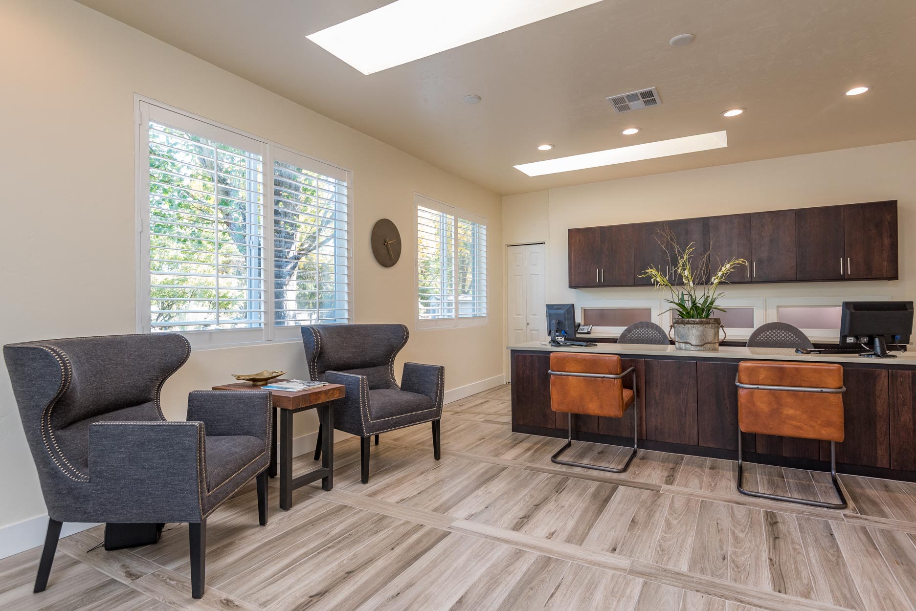 a living room with a desk and chairs and a kitchen