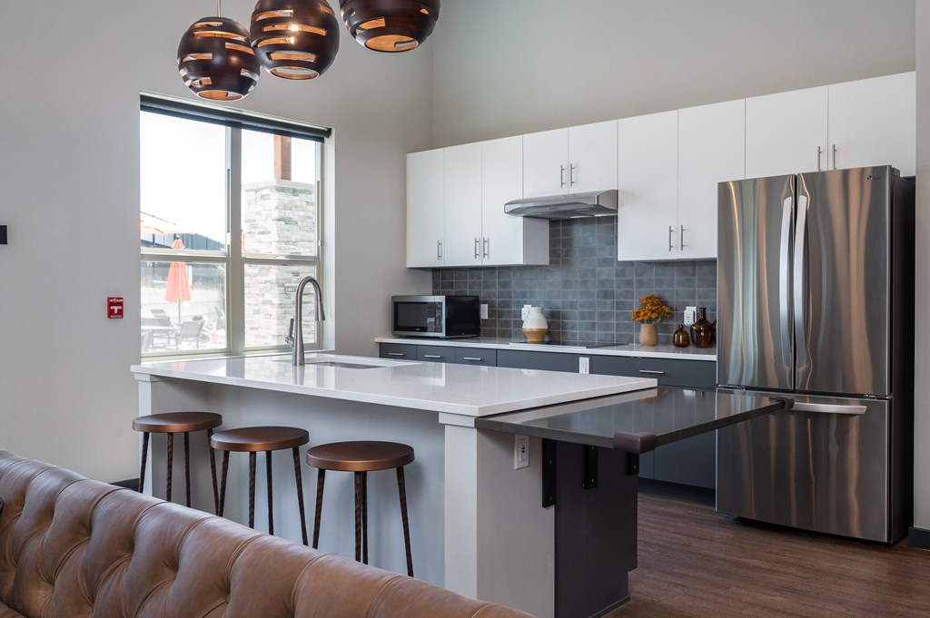 A modern kitchen with a refrigerator, stove, and bar stools.