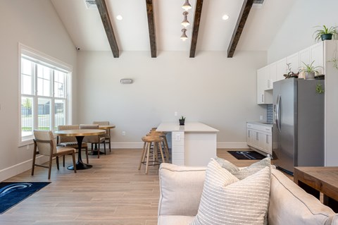 A kitchen with a refrigerator, table, and chairs.