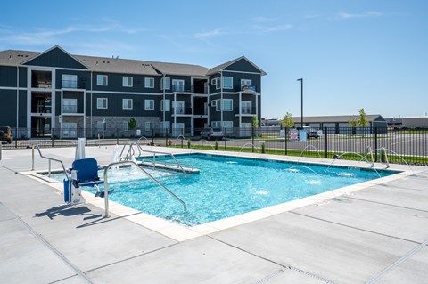 A swimming pool in front of a multi-story apartment building.