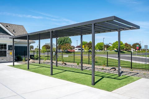 A bus stop shelter with a metal frame and a roof is located on a sidewalk.