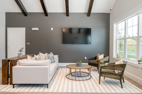 A room with a white couch, a coffee table, and a flat screen TV mounted on the wall.