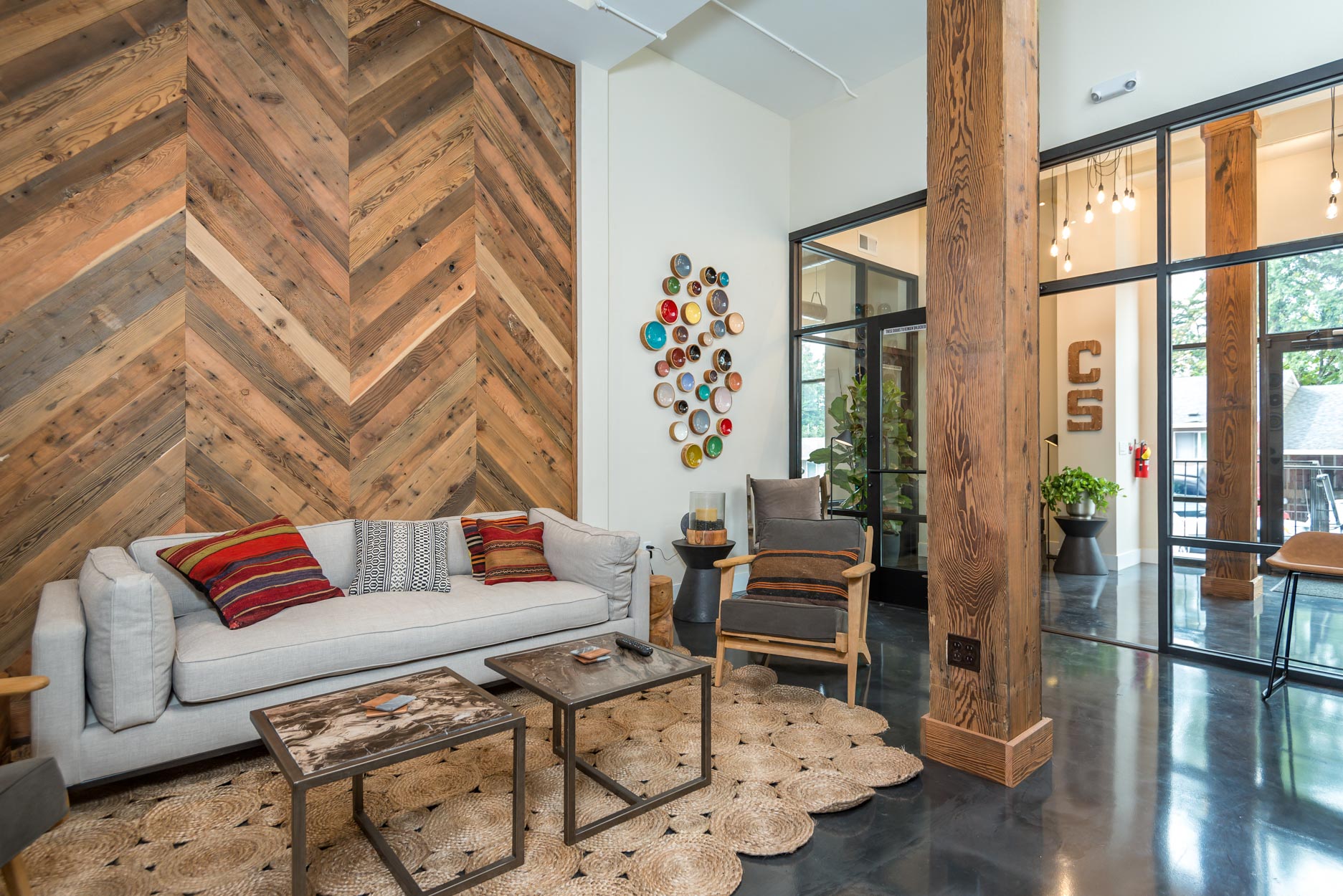 a living room with a couch and tables in front of a wood wall