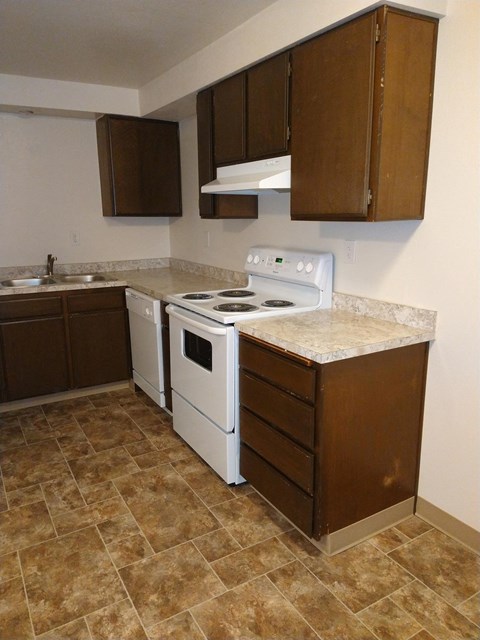 A kitchen with brown cabinets and a white stove top oven.