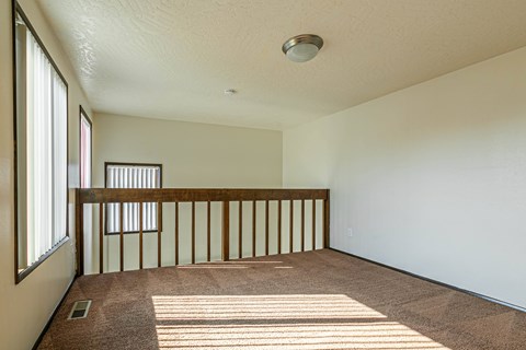 A room with a carpeted floor and a window on the left side.