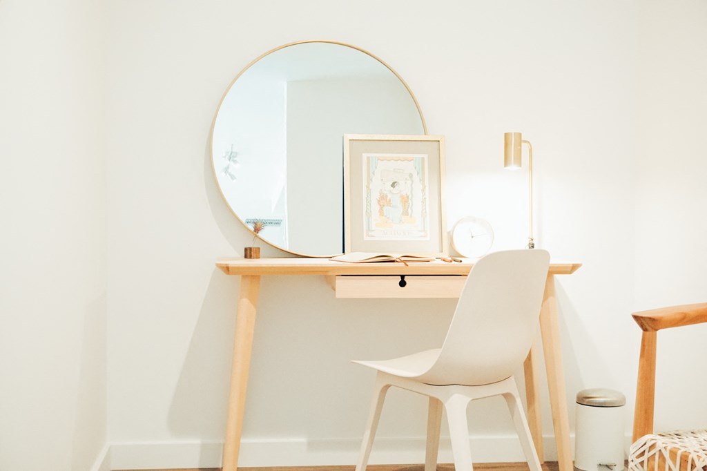 a desk with a mirror and a chair in a room
