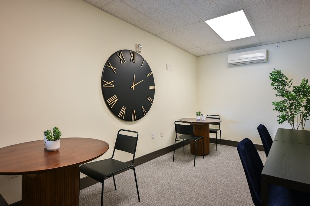 a room with a large clock on the wall and tables and chairs