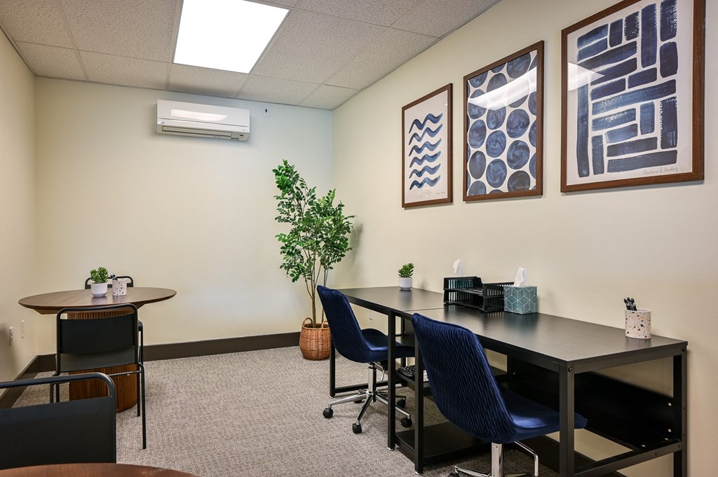 a conference room with a table and chairs and paintings on the wall