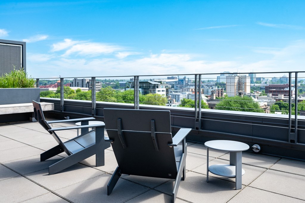 a terrace with two chairs and a table with a view of the city in the background