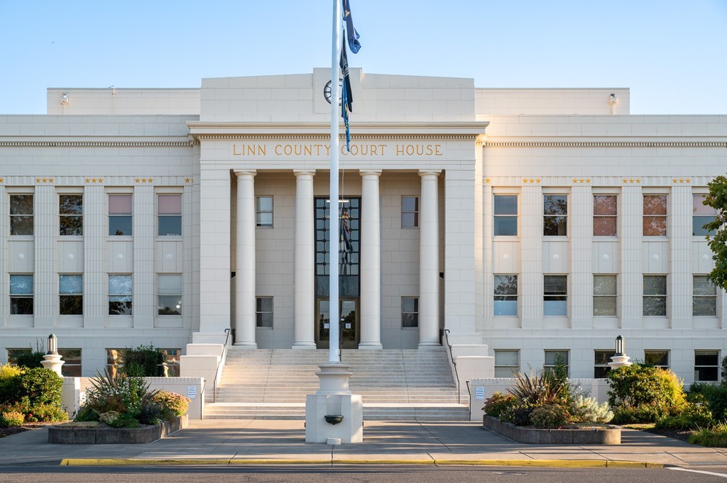 The Linn County Court House is a large, white building with a flag flying in front.