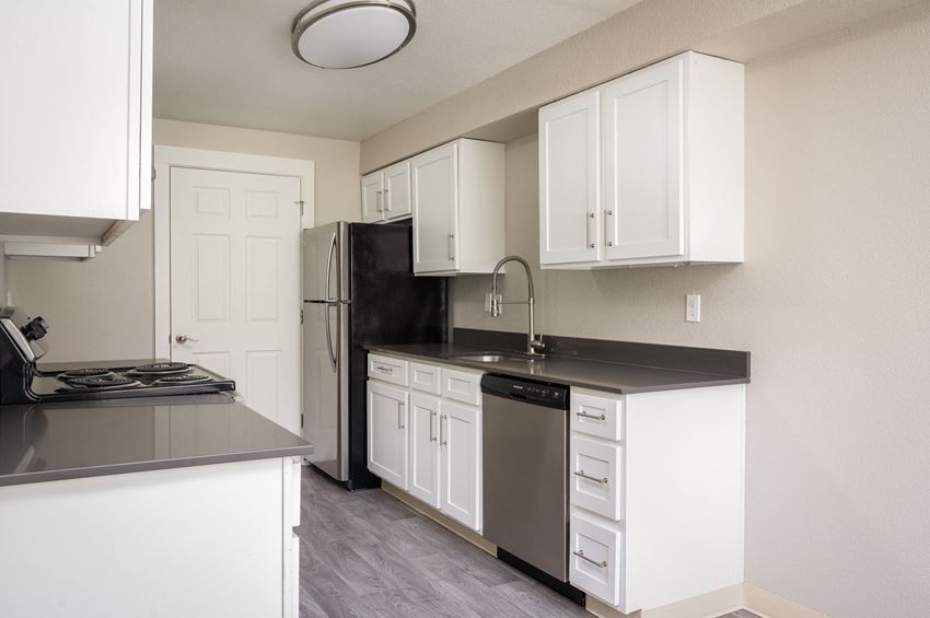a kitchen with white cabinets and black countertops - Photo Gallery
