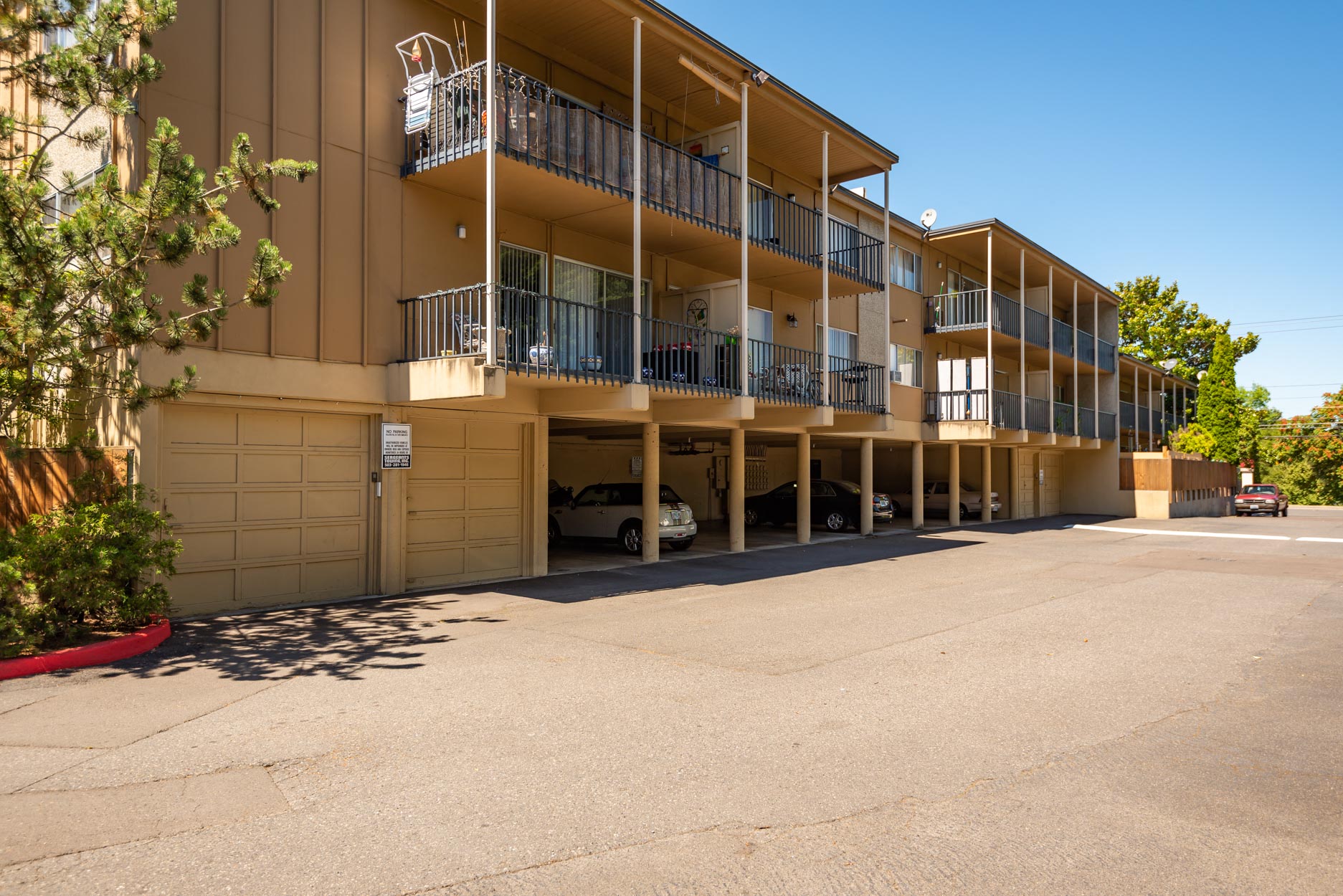 Exterior view of apartments with balconies and parking underneath.