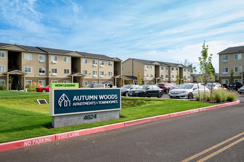 an exterior view of an apartment complex with cars in the parking lot