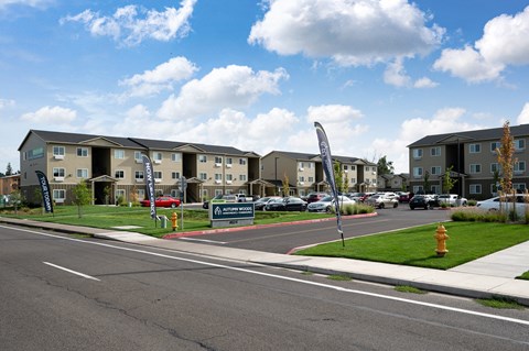 a street with an apartment complex with cars parked in front of it