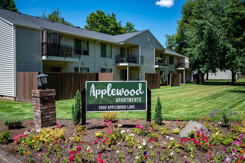 A sign for Applewood Apartments is in front of a building.